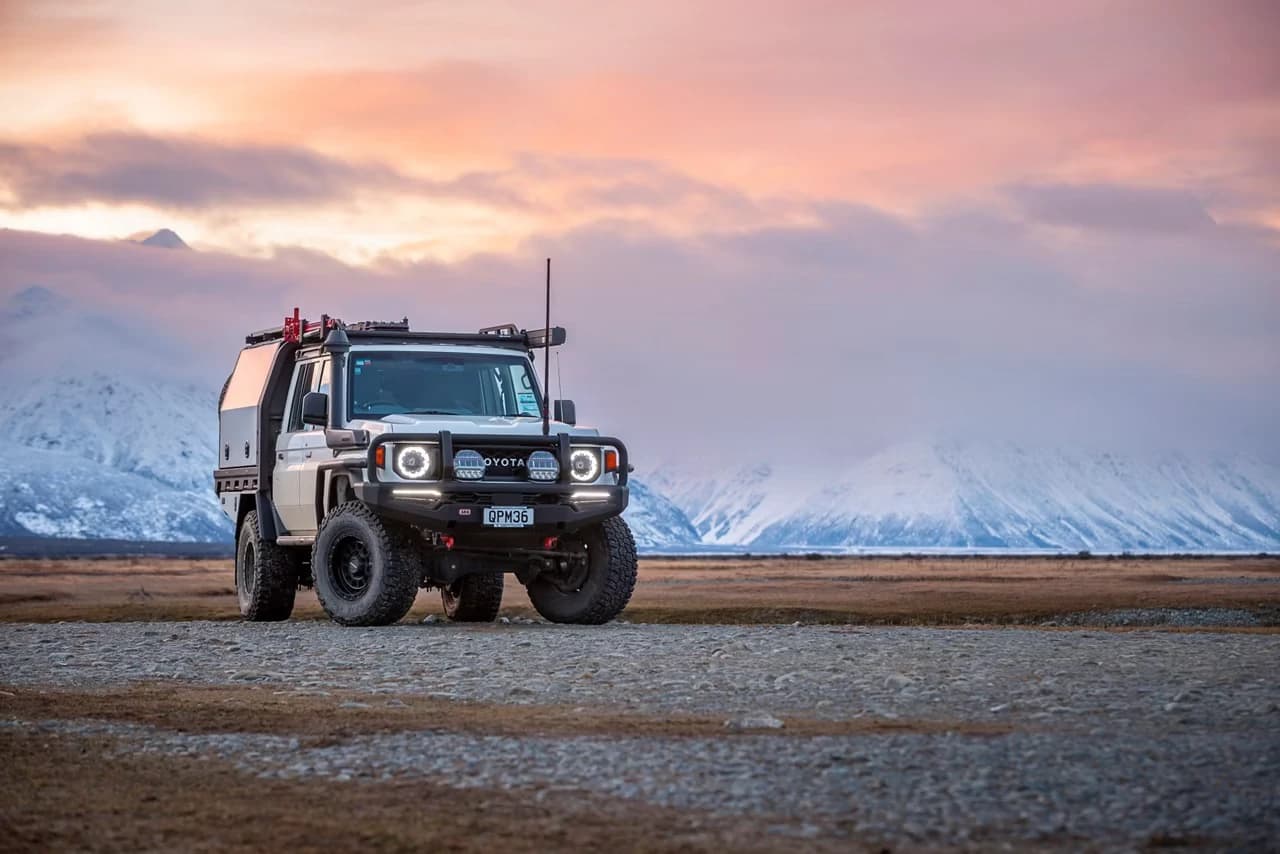Expedition-equipped 4x4 in front of snow-covered mountains
